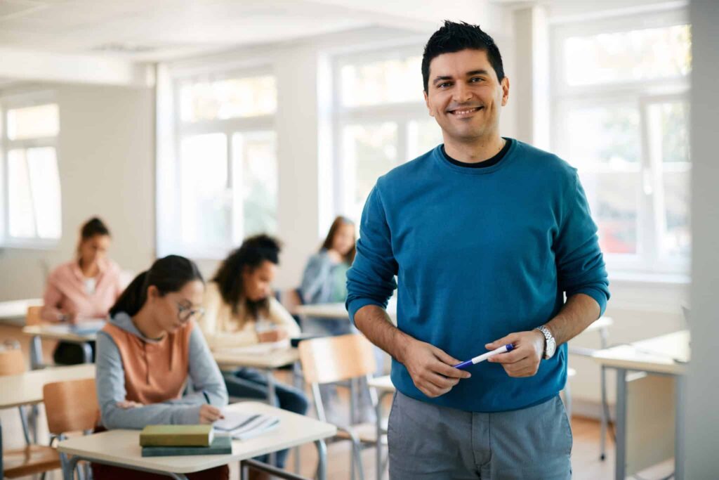 School Professionals Teacher Posing in Classroom | Substitute Teacher Staffing Agency, Test Proctoring, Teacher Recruitment, and Tutoring Services