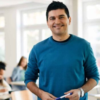School Professionals Teacher Posing in Classroom | Substitute Teacher Staffing Agency, Test Proctoring, Teacher Recruitment, and Tutoring Services